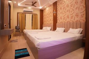 a bedroom with two beds and a ceiling fan at Hotel ganga sarovar Inn in Deoghar