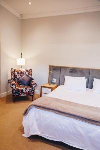 a bedroom with a large bed and a chair at Suite 273 - Luxe Solar Suite - Heated Pool in Cape Town +48 photos