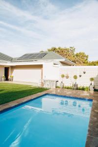 a house with a blue swimming pool in front of a house at Suite 273 - Luxe Solar Suite - Heated Pool in Cape Town