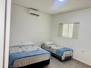 a bedroom with two beds and a window at HOTEL ITAPUÃ vg in Várzea Grande