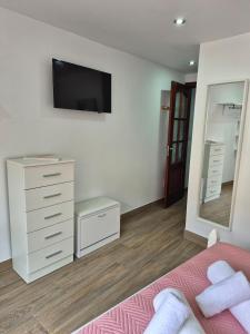 a bedroom with a dresser and a tv on the wall at Casa Beleví - Laxe, sea and rest in Laxe