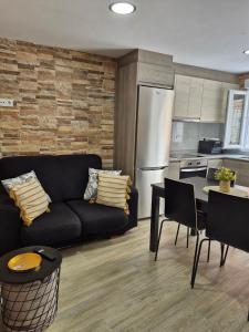 a living room with a black couch and a kitchen at Casa Beleví - Laxe, sea and rest in Laxe