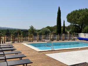 a swimming pool on a wooden deck with chairs around it at Résidence Le Petit Duc in Carcassonne