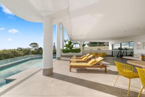 an open living room with yellow chairs and a swimming pool at Sakara at Marochydore in Maroochydore