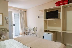 a bedroom with a bed and a tv and a table at Pousada Cataratas in Foz do Iguaçu