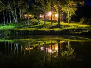 a reflection of a building in a pond at night at Cabana Liberdade in Rio dos Cedros