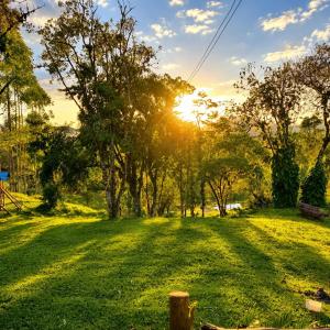 a sunset in a field with trees and grass at Cabana Liberdade in Rio dos Cedros