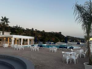 a patio with tables and chairs next to a pool at Villaggio Hotel Agrumeto in Capo Vaticano