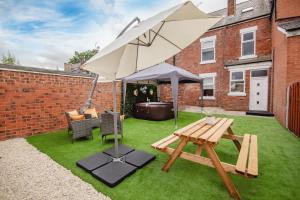 a patio with an umbrella and a picnic table at Groups Haven 5 Bed 2 Bath Hot Tub Pool Table in Attercliffe