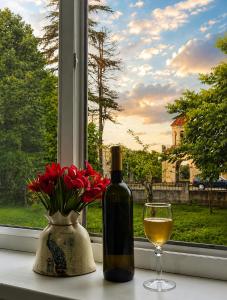 a bottle of wine and a vase with flowers and a glass at Elasia in Martvili