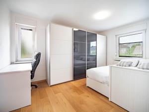 a white bedroom with a bed and a desk at Grand Family Residence Ljubljana in Ljubljana