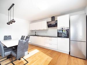 a kitchen with white cabinets and a table and a refrigerator at Grand Family Residence Ljubljana in Ljubljana