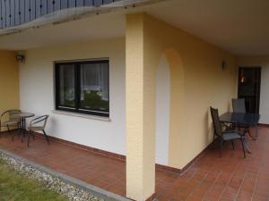 eine Terrasse mit Stühlen, einem Tisch und einem Fenster in der Unterkunft Ferienwohnung am Eck in Amorbach