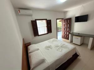 a bedroom with a bed with white sheets and a window at Pousada Coqueiro do Caitá in Morro de São Paulo +34 photos