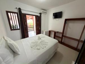 a bedroom with a white bed and a television at Pousada Coqueiro do Caitá in Morro de São Paulo