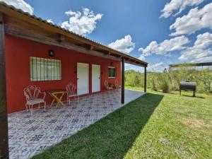 a red house with a patio with chairs and a grill at Aires del Ibera in Colonia Carlos Pellegrini