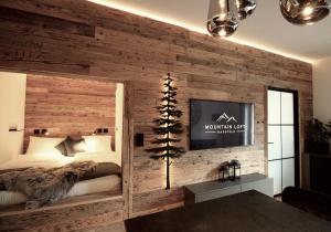 a bedroom with a wooden wall with a bed and a tv at Mountain Loft Nassfeld in Tröpolach