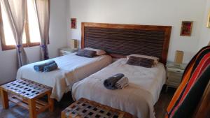 a bedroom with two beds and a table and windows at Cabañas La Nochera in Tilcara