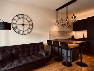 a living room with a couch and a clock on the wall at Mountain Loft Nassfeld in Tröpolach +6 photos