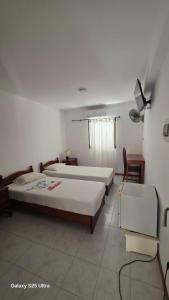 a bedroom with two beds and a table and chairs at Residencial Raiar in Mindelo