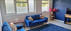 a living room with a blue couch and a tv at Comfortable Guesthouse Stratford upon avon in Stratford-upon-Avon