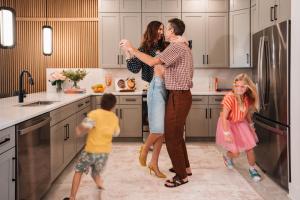 a family standing in a kitchen with a refrigerator at Villatel Orlando Resort in Orlando
