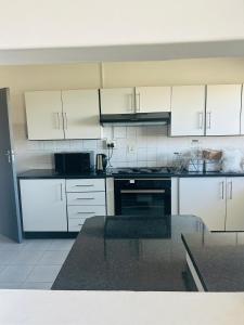 a kitchen with white cabinets and a black oven at Alwaba guest house in Mthatha