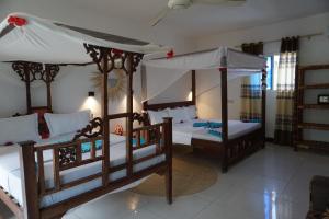a bedroom with two beds and a canopy at Cocolala Beach House in Nungwi