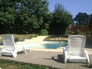 two white chairs sitting next to a swimming pool at penty Broceliande 3 personnes in Guilliers