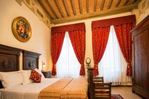 a bedroom with a bed and two windows at All'Ombra della Torre a due passi da Piazza del Campo in Siena +11 photos