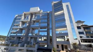 a tall apartment building with a blue sky in the background at Apto Rosas| 3Q, todo Climatizado, Prox das Termas in Piratuba