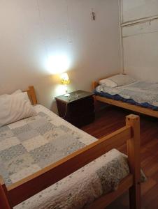 a room with two beds and a table with a lamp at Casa 3 dormitorios estacionamiento Heriberto Ortiz in Santiago