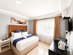 a bedroom with a large bed and a television at TLMZ Guesthouse in Newcastle +18 photos