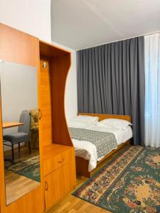 a small bedroom with a bed and a mirror at Barskhan Guest House in Bosteri