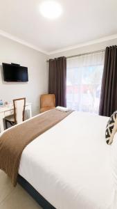 a bedroom with a large white bed and a window at TLMZ Guesthouse in Newcastle