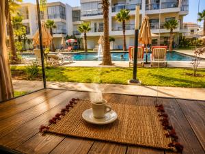 a cup of coffee on a table in front of a pool at Pool View Apartment Gated Residence in Sidi Rahal