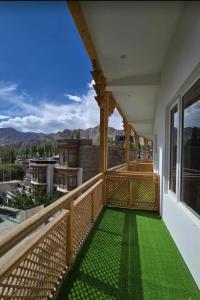 a balcony with green flooring and a view of the mountains at Hotel Royal EdelWeiss in Leh