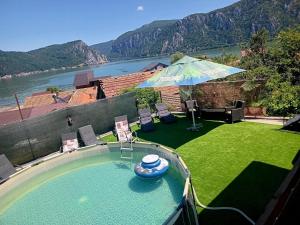 a swimming pool with chairs and an umbrella in a yard at DiBosco House in Dubova