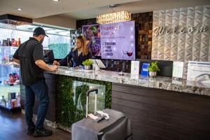 a man standing at a bar with a woman behind a counter at Hotel Velario in Tijuana