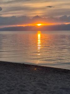 a sunset on the beach with the sun setting at Aihan guest house in Pokrovka +18 photos