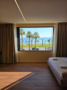 a bedroom with a large window with a view of the beach at Haris Hotel & Suites in Vlorë