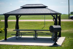 a picnic table with a roof and a grill at Clara City Inn in Clara City
