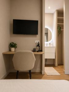 a living room with a chair and a television on the wall at Le Mas d'Elio in Cheval-Blanc