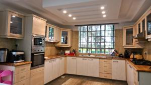 a kitchen with white cabinets and a large window at Malala River House in Arusha