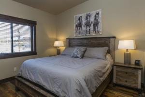 a bedroom with a bed with a picture of horses on the wall at Cana Loft 301 in Whitefish