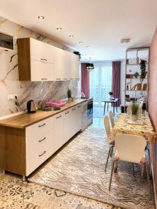 a kitchen with white cabinets and a dining table at Apartman Bambi Vlašić in Vlasic