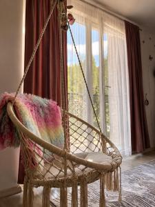a swing chair with a blanket in a room with a window at Apartman Bambi Vlašić in Vlasic