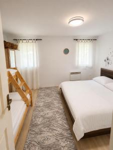 a white bedroom with two beds and a rug at Apartman Bambi Vlašić in Vlasic