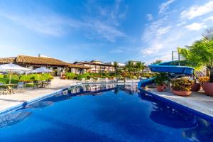 a pool at a resort with tables and chairs at Hotel Praia do Sol in Ilhéus