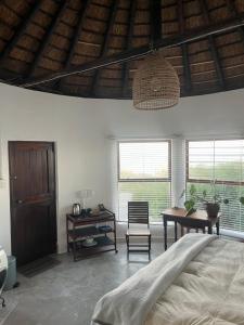 a bedroom with a bed and a table and windows at Rondawel with sea view in Kleinmond